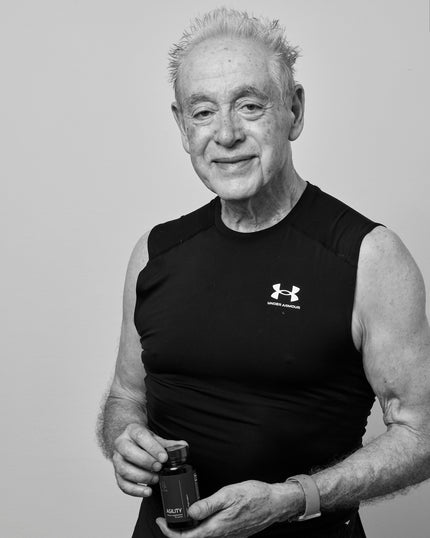 Man wearing sleeveless shirt holding a bottle against a plain background