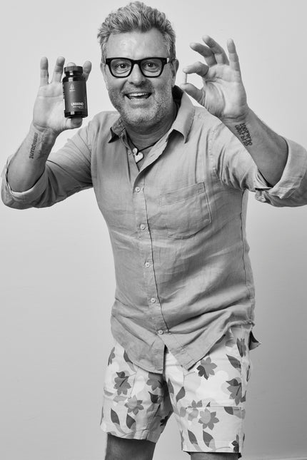 Man holding a supplement bottle with a neutral background