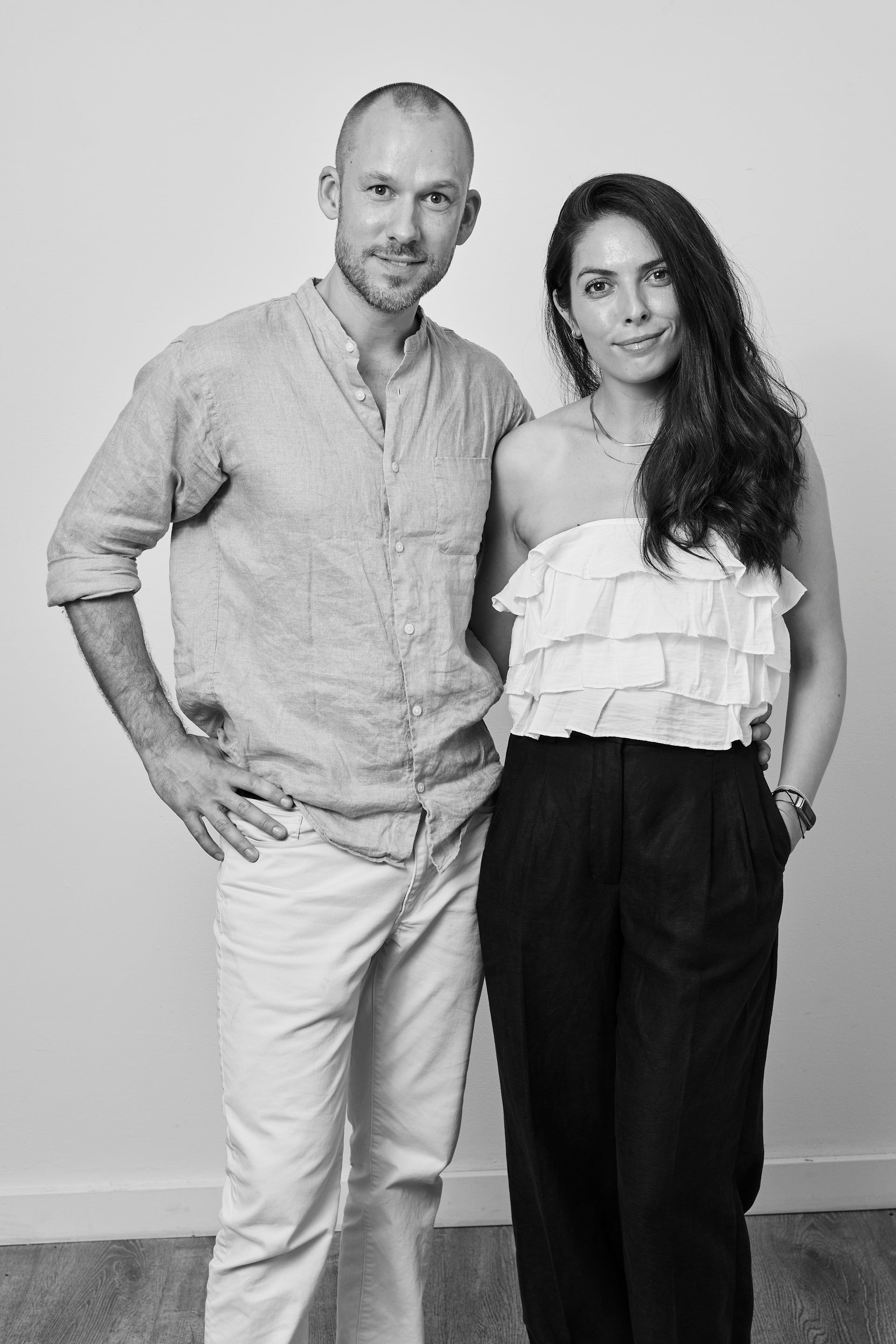 Black and white photo of a man and woman standing close together against a plain background